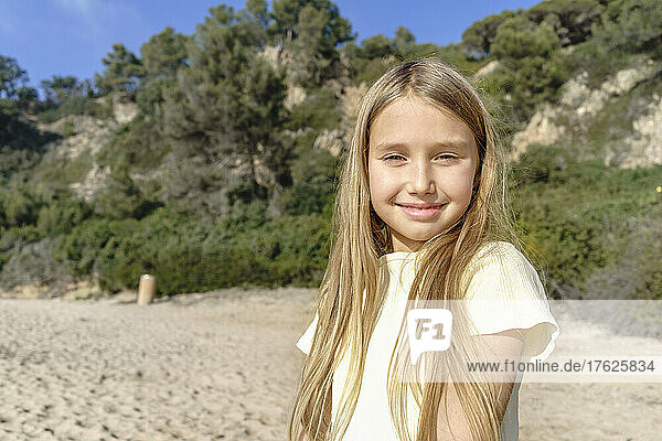 Smiling blond girl at beach on sunny day