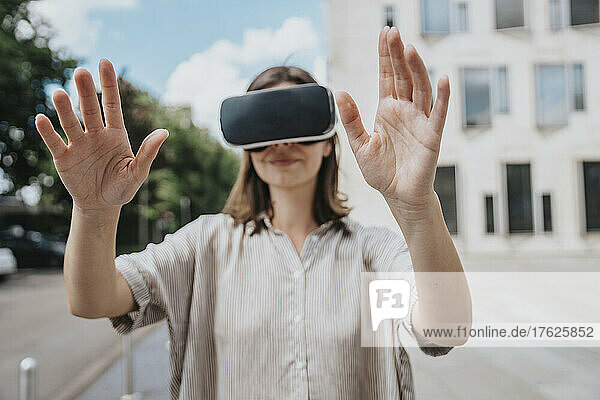 Woman gesturing wearing virtual reality headset at street