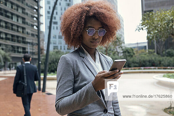 Young businesswoman using smart phone outdoors