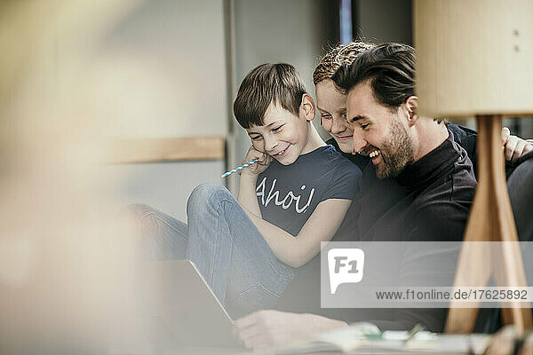 Happy man with sons using laptop at home