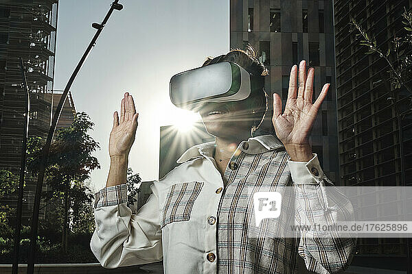 Businesswoman wearing virtual reality simulator gesturing on sunny day