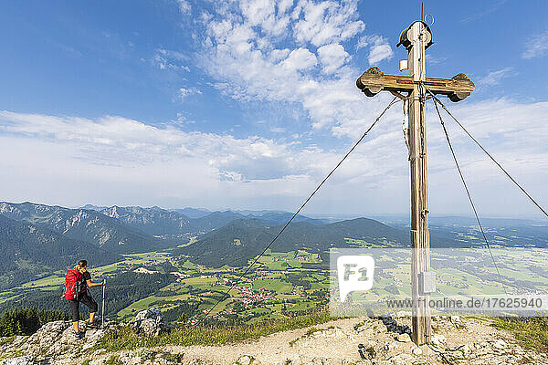 Female hiker admiring view from Bockstein with summit cross in foreground