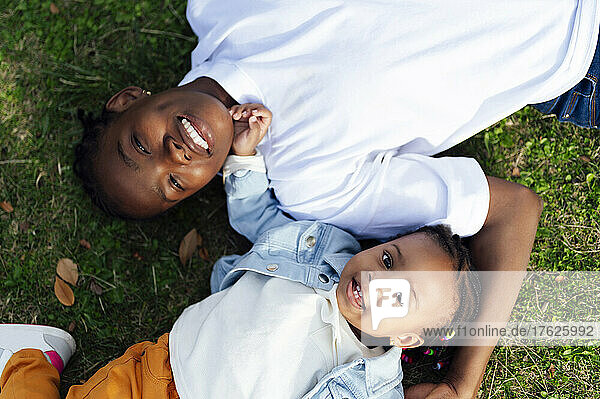 Happy mother with daughter lying on grass at park