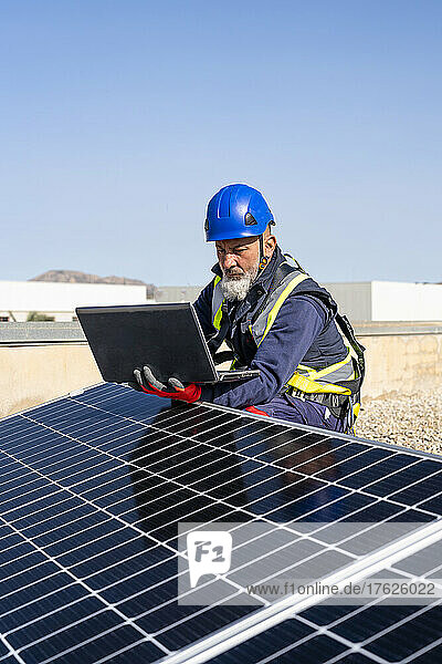 Engineer working on laptop by solar panels