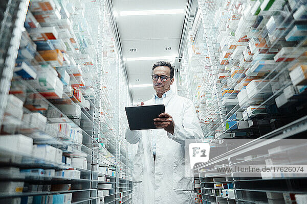 Pharmacist with tablet computer taking inventory in pharmacy