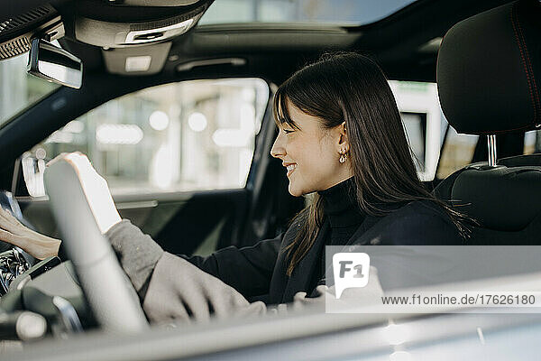 Smiling businesswoman using control panel of electric car