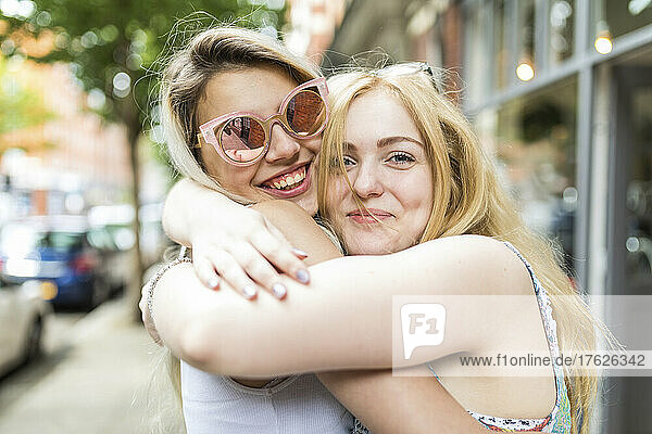 Happy teenage girls with blond hair hugging each other