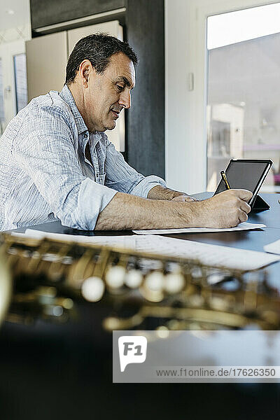 Saxophonist writing musical notes by tablet PC on table at home