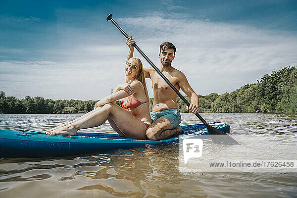 Man paddleboarding with woman on lake