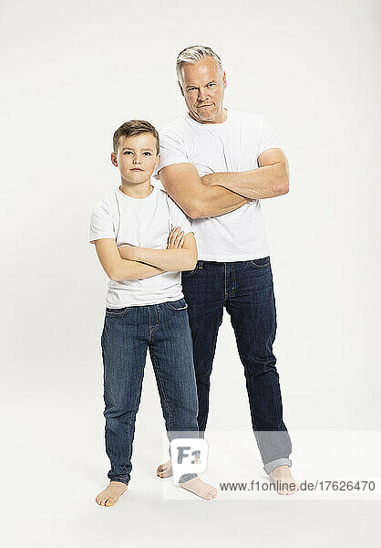 Father and son standing with arms crossed in studio
