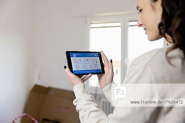 Young woman using app on tablet PC at home renovation work