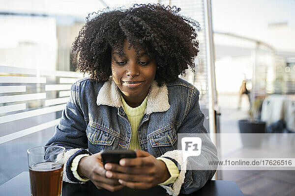 Young woman using mobile phone sitting at cafe