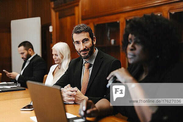 Portrait of confident businessman sitting with colleagues in board room