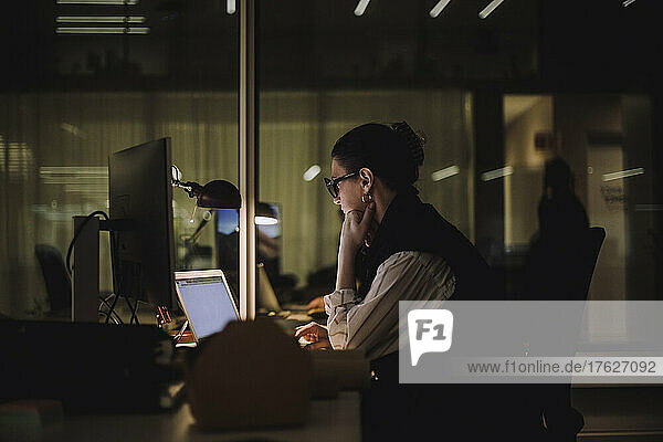 Ehrgeizige Geschäftsfrau  die einen Laptop benutzt  während sie nachts im Büro arbeitet