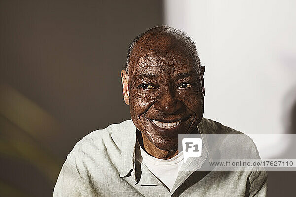 Smiling senior man looking away against white background