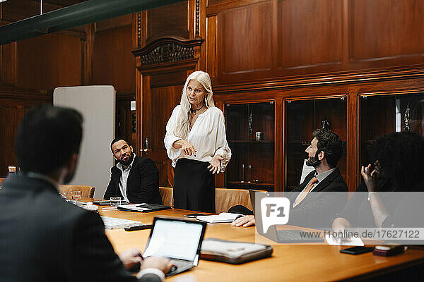 Confident businesswoman discussing with lawyers in board room during conference meeting