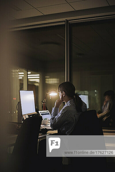 Young businesswoman working on computer late night in office