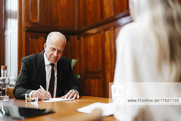 Älterer Geschäftsmann bei der Unterzeichnung eines Vertrags mit einem Finanzberater im Sitzungssaal