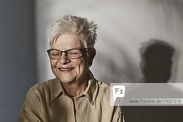Glückliche ältere Frau mit Brille auf weißem Hintergrund