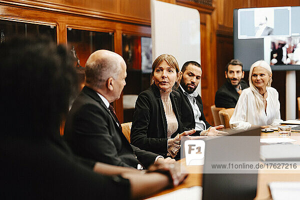 Businesswoman discussing strategy with financial advisors in board room during conference meeting