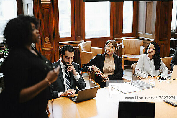 Weibliche Kollegen betrachten eine Geschäftsfrau während einer Konferenzsitzung im Sitzungssaal