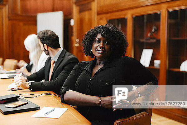 Porträt einer selbstbewussten Geschäftsfrau mit verschränkten Händen  die während einer Sitzung im Sitzungssaal sitzt