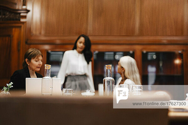 Flaschen und Gläser auf dem Tisch  im Hintergrund Finanzberaterinnen am Arbeitsplatz