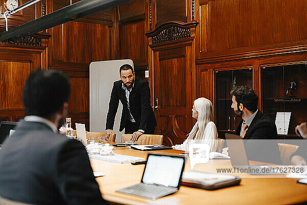 Businessman discussing with colleagues in board room during conference meeting