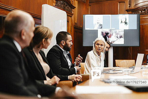 Female financial expert discussing with colleagues in meeting at board room