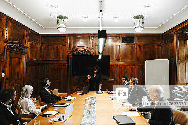 Geschäftsfrau mit multirassischen Kollegen  die während einer Konferenzsitzung im Sitzungssaal diskutieren