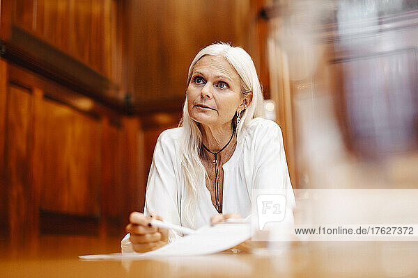 Selbstbewusste Geschäftsfrau sitzt mit Vertragsdokument im Sitzungssaal