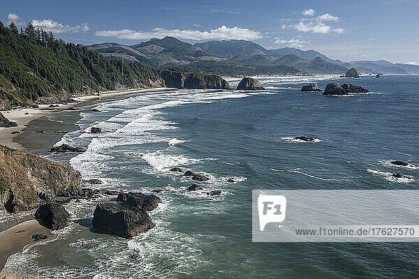 Cannon Beach with waves breaking on rocky shoreline from above.