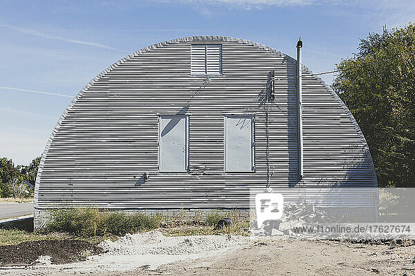 A grey metal barn on a roadside in a small town in Nebraska.