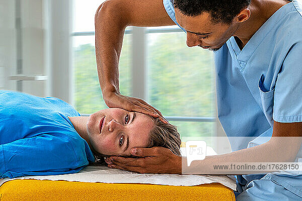 Close up of physiotherapist manipulating young woman. Girl laying on spa bed with hands massaging