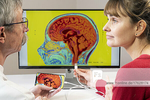 Researcher explaining to a woman how a smartphone can be connected to a brain.