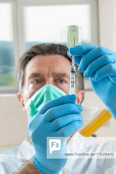 The doctor fills a syringe with vaccine.