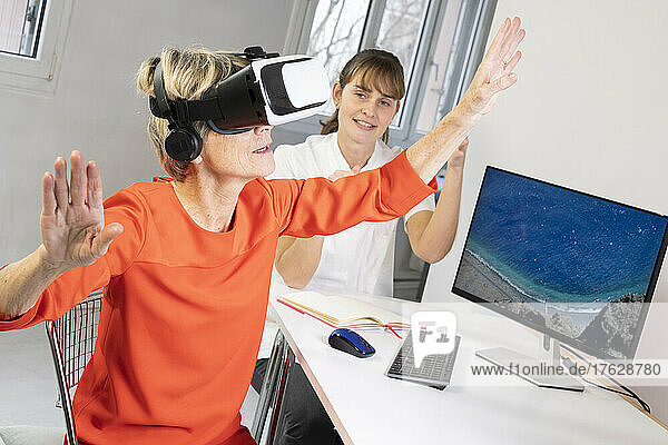 Elderly woman  during a therapy session with a virtual reality headset under the supervision of a therapist.