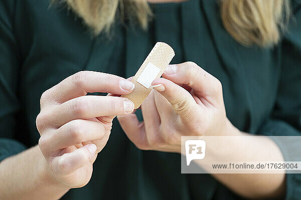 Young woman putting a bandage on her finger.