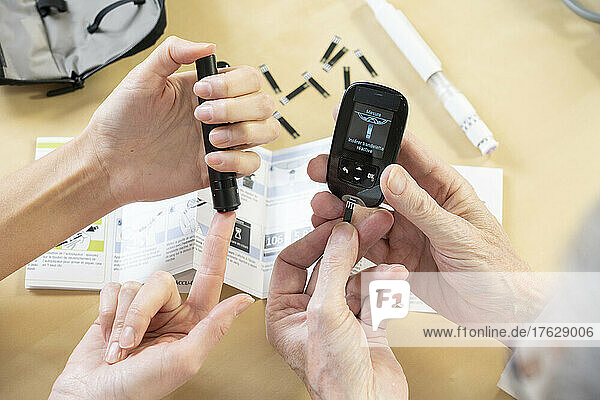 Close-up of a woman's hands and a doctor's hands explaining how to measure her blood sugar and treat her diabetes.