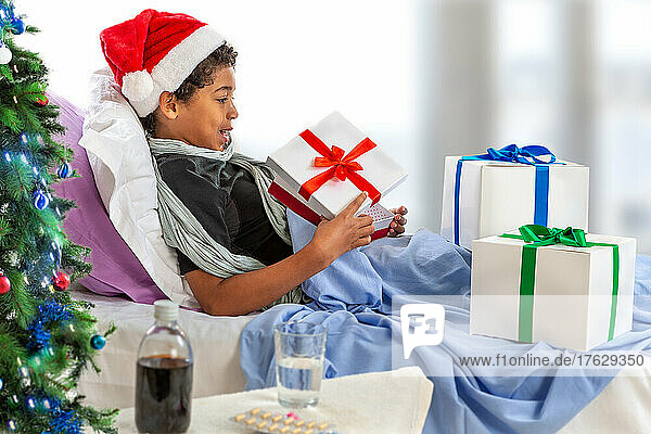 Little boy wearing Santa hat receiving her gift while she is in hospital
