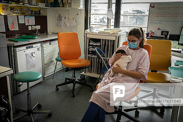 A midwife takes care of a premature baby while the mom is busy.