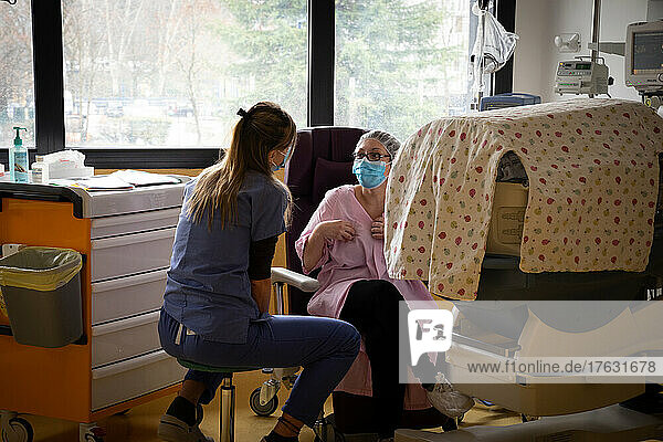 A nurse talks to a mom. The baby's bed is hidden so that it is in the dark.
