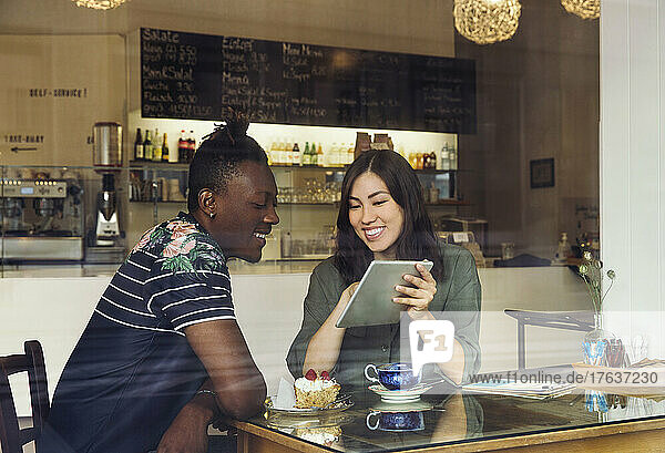 Smiling couple looking at digital tablet in cafe