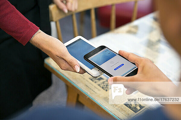 Close-up of man paying with smart phone in restaurant