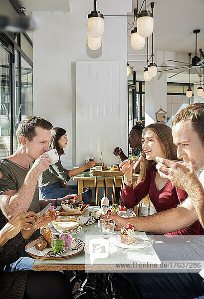 Group of smiling friends enjoying breakfast in restaurant