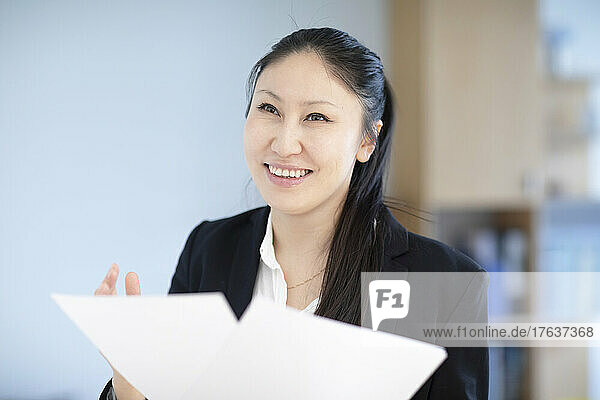 Smiling businesswoman with documents in office