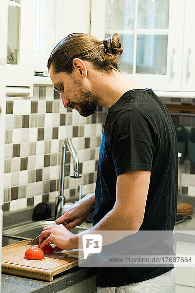 Man cutting tomato in kitchen