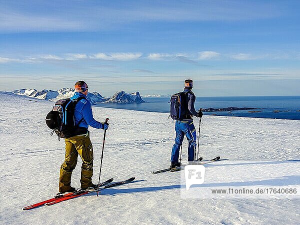 Two ski mountaineers with a view of the sea  Teisten in the background  Bergsjforden  Senja Island  Troms  Norway  Europe