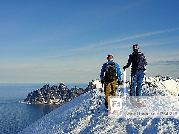 Zwei Skibergsteiger am Gipfel des Husafjellet mit Blick auf Devils Teeth  Okshornan  Insel Senja  Troms  Norwegen  Europa