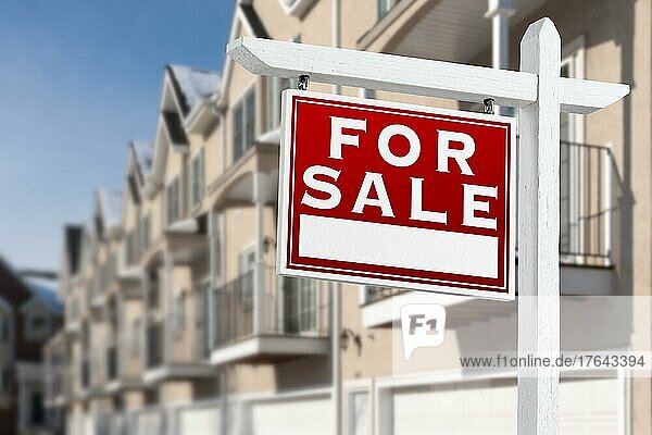 Zu verkaufen Immobilien Schild vor einer Reihe von Eigentumswohnungen Balkone und Garagentore